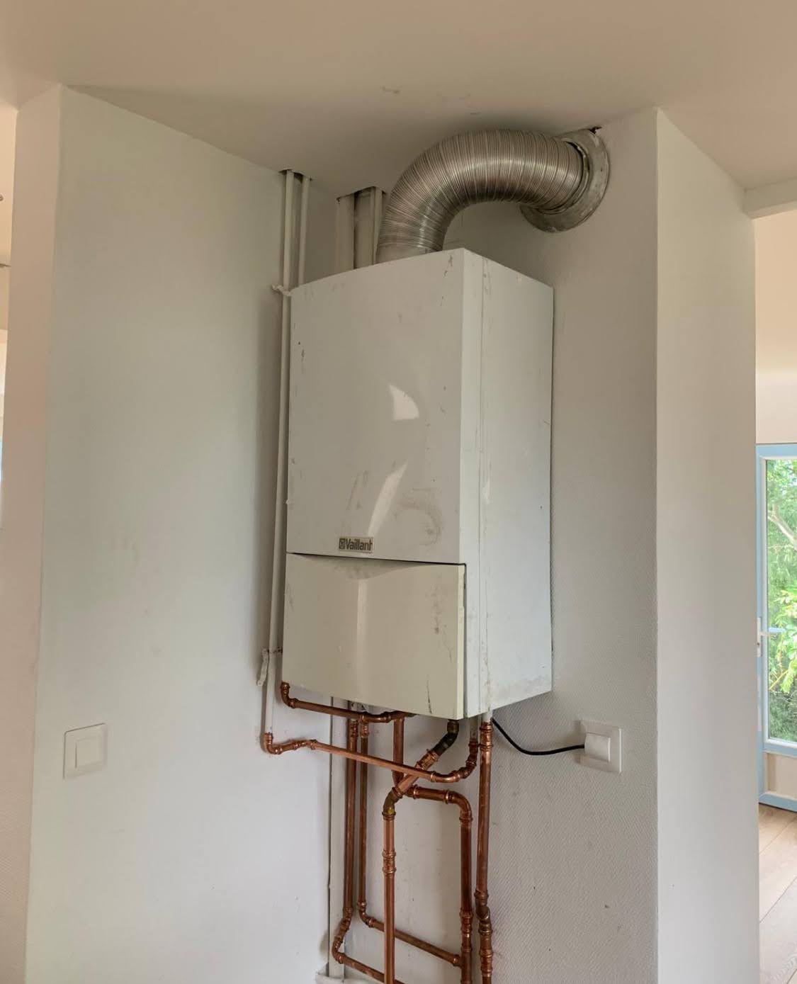 Ancienne chaudière murale gaz Vaillant avec conduit d'évacuation flexible en aluminium, nécessitant un entretien chaudière à Bischheim en urgence par un plombier chauffagiste.