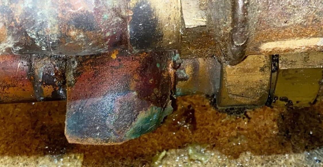 Détail de l'éclatement du métal près d'un raccord en laiton oxydé, illustrant les dégâts du gel avant une réparation de tuyauterie à Brumath.