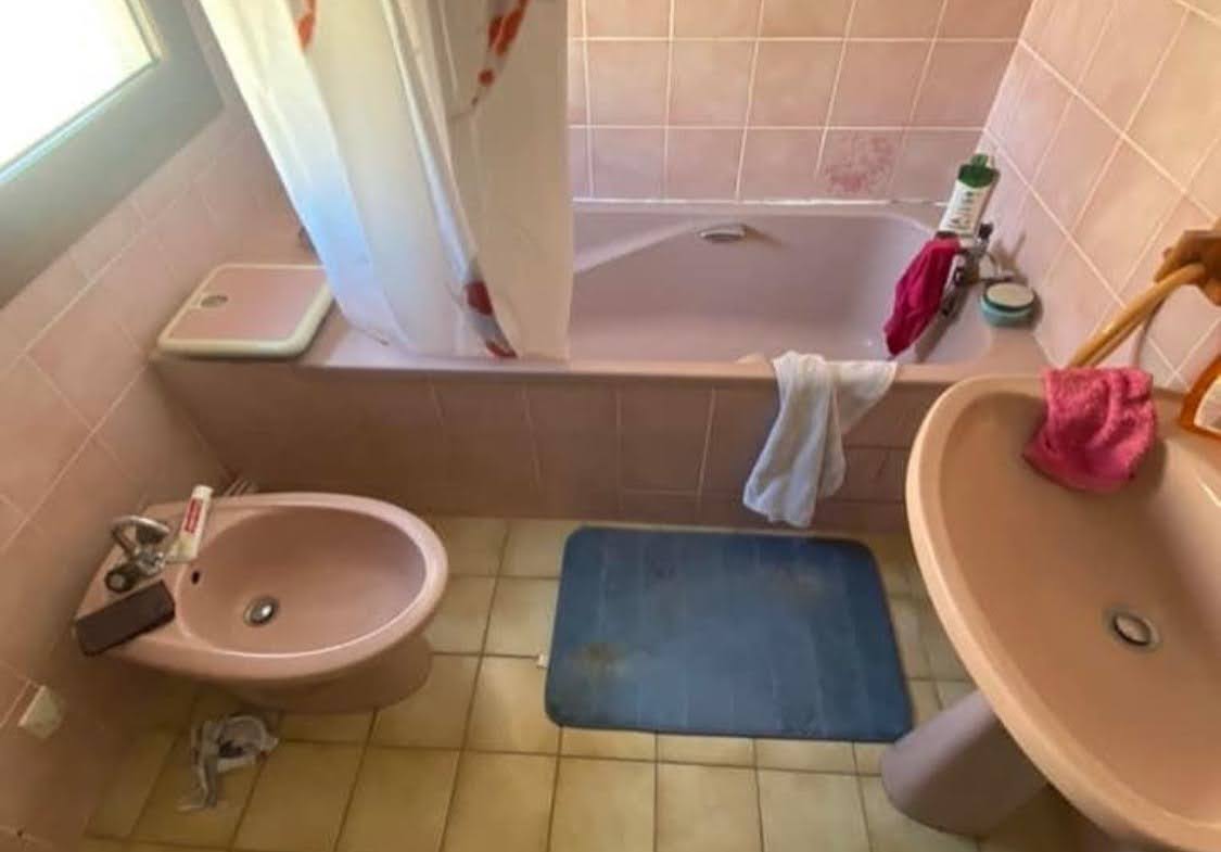 Salle de bain obsolète avec baignoire rose et bidet avant une transformation PMR à Colmar.