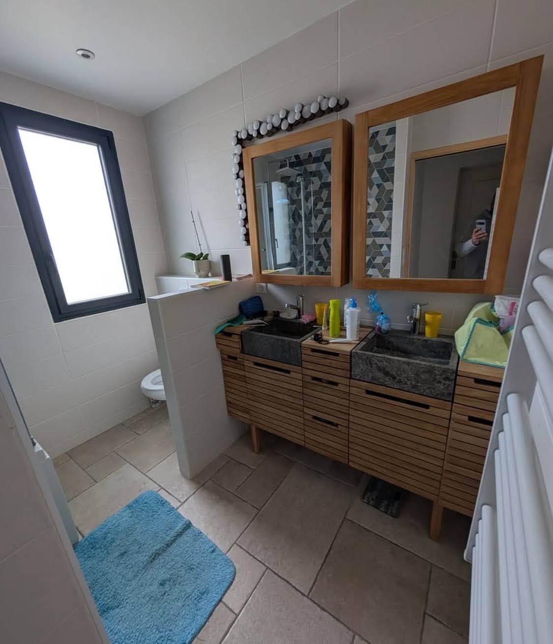 État initial avant une rénovation complète de salle de bain à Molsheim, montrant un ancien meuble en bois à lattes, une double vasque en pierre massive et un muret de séparation.