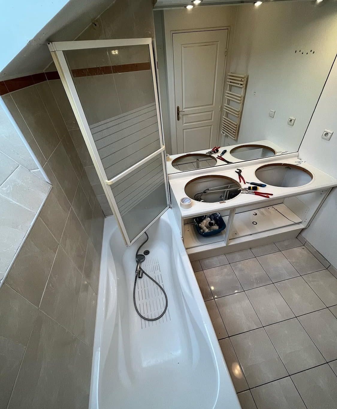 Ancienne salle de bain mansardée avec une baignoire classique, un carrelage beige et un meuble encombrant avant un réagencement complet et sur mesure à Obernai.