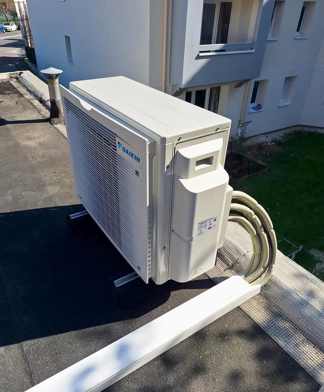 Groupe extérieur de climatisation réversible Daikin posé sur des supports anti-vibratiles sur l'étanchéité bitumineuse d'un toit-terrasse lors d'une installation à Obernai.