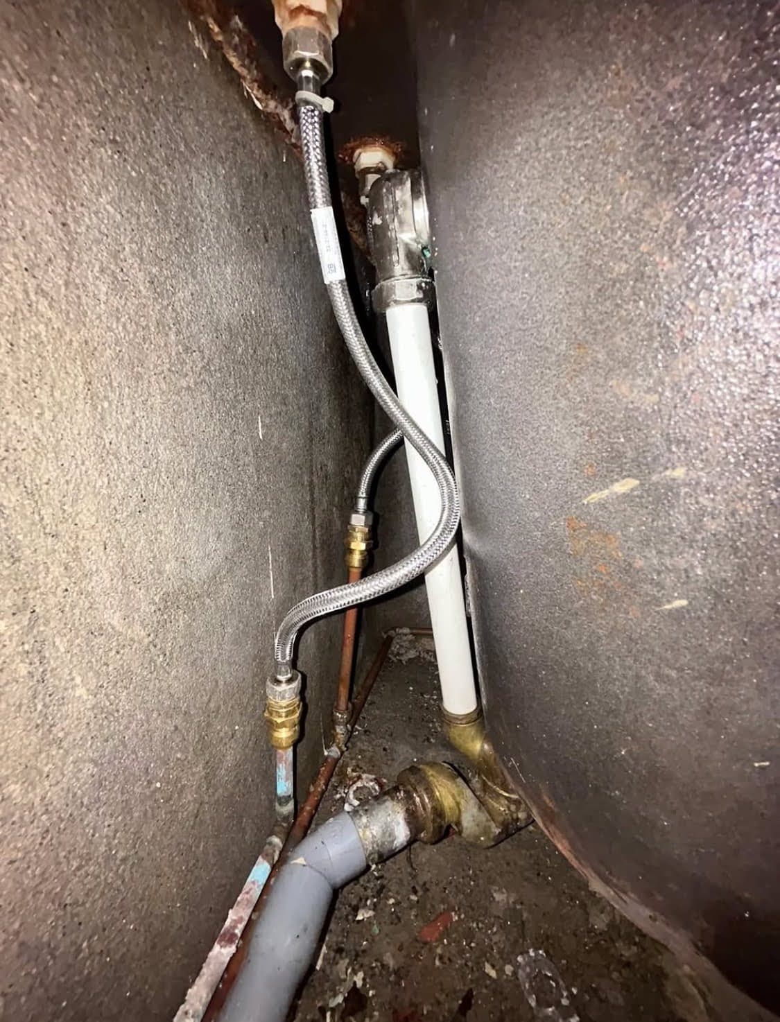 Résultat du dépannage par un plombier : tuyau en cuivre coupé, raccord en laiton posé et connexion d'un flexible sanitaire tressé au mitigeur de la baignoire.