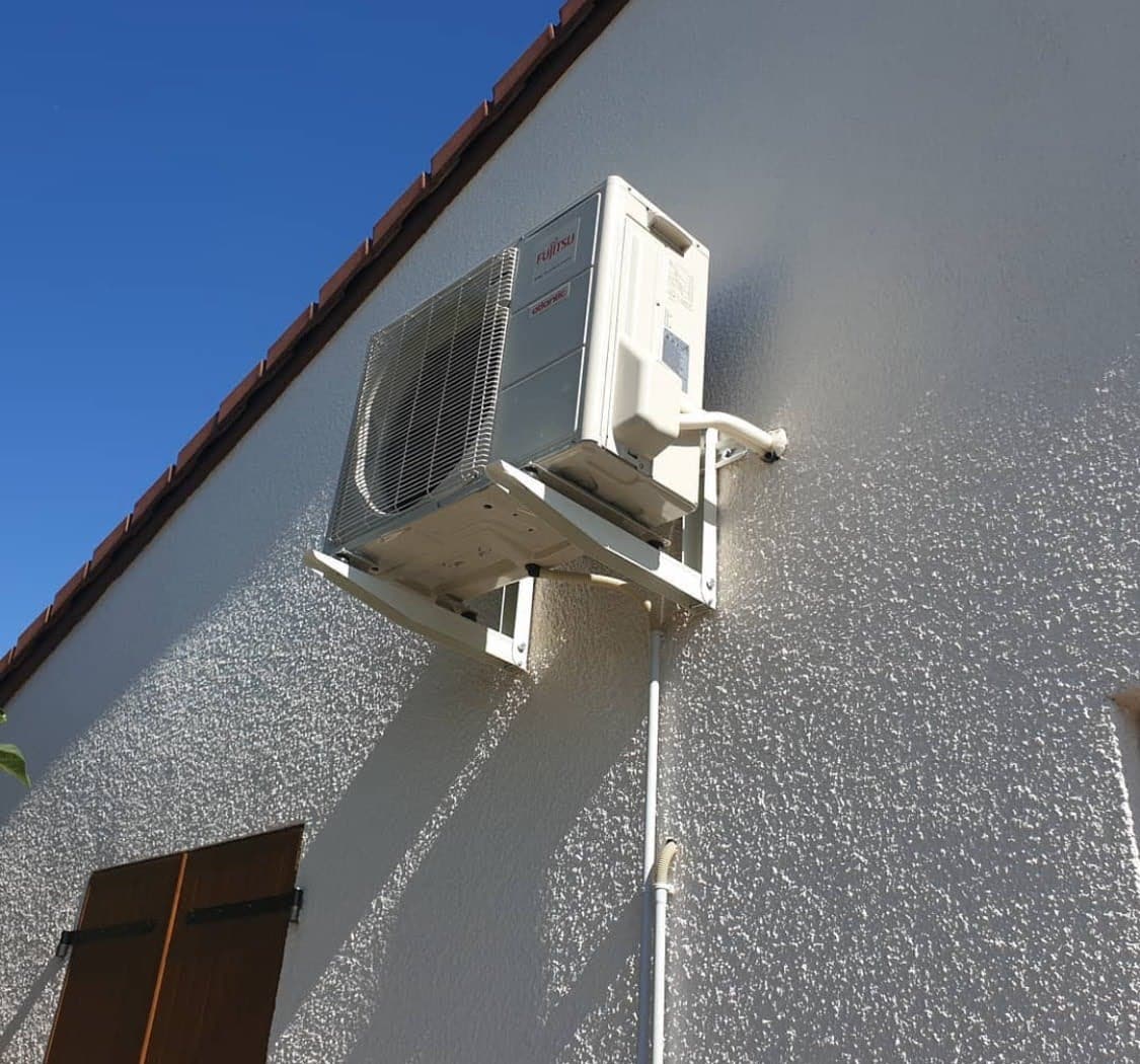 Installation technique d'une unité extérieure de climatisation Fujitsu Atlantic fixée sur un support mural renforcé en hauteur sur une façade à Schiltigheim.