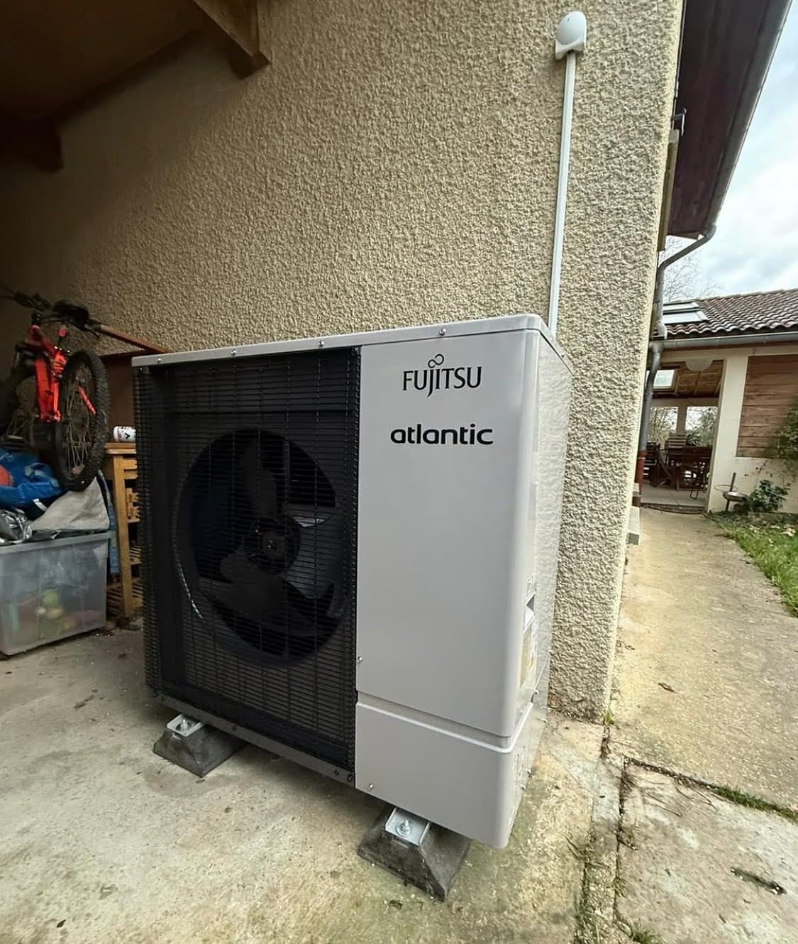 Unité extérieure d'une pompe a chaleur à Strasbourg, secteur Lingolsheim, posée sur des plots anti-vibratiles (Big Foot) avec grille de protection du ventilateur.