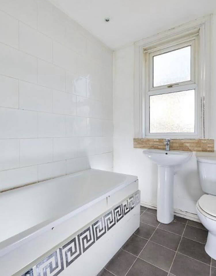 Salle de bain datée avec lavabo sur colonne et carrelage blanc avant une rénovation complète à Illkirch.