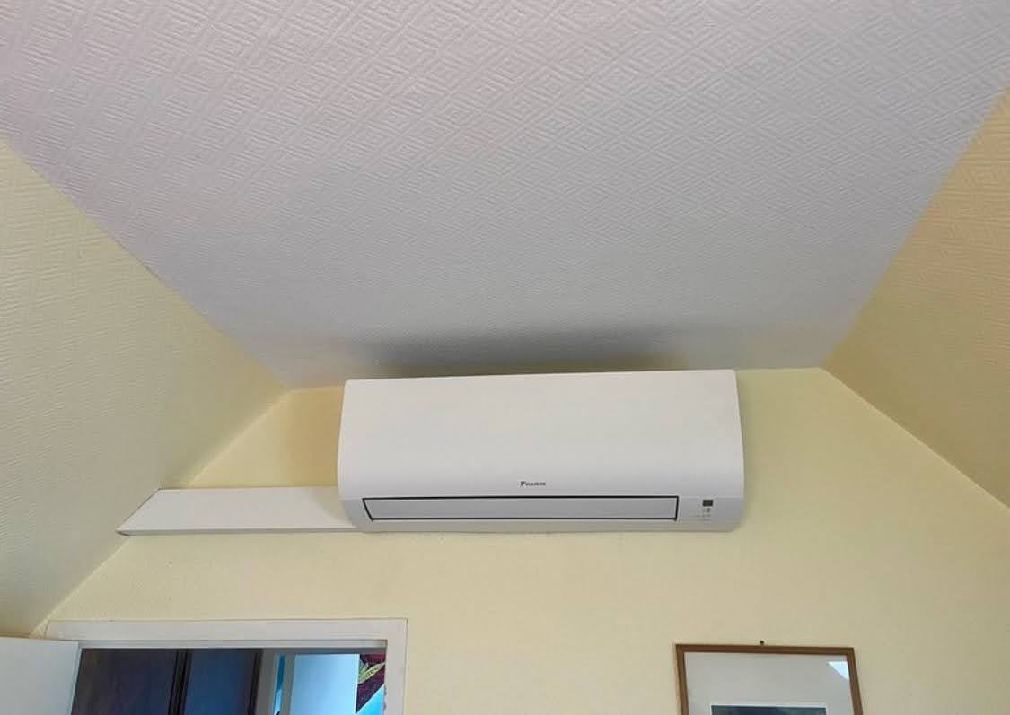 Unité intérieure murale blanche de marque Daikin installée sous un plafond mansardé, illustrant une pose de climatisation esthétique et optimisée à Obernai